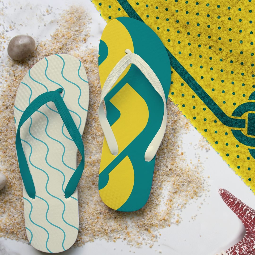 Dois chinelos com estampas da marca sobre areia: um creme com ondas verde-água e outro em verde-petróleo e amarelo com um detalhe ampliado do nó, ao lado de uma canga amarela de bolinhas com o nó da Crochart