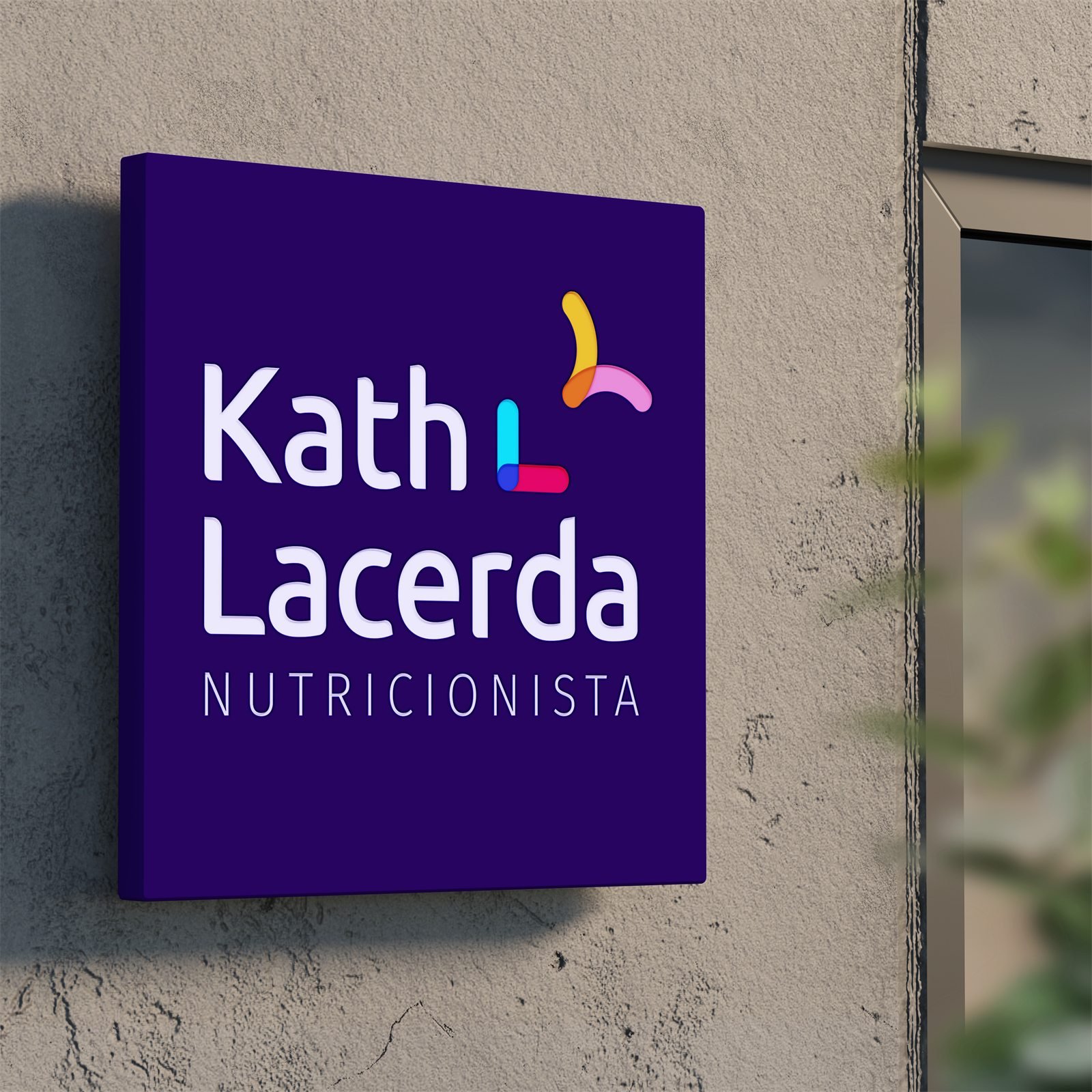 Placa quadrada roxa com a assinatura Kath Lacerda Nutricionista, fixada numa parede externa ao lado de uma janela