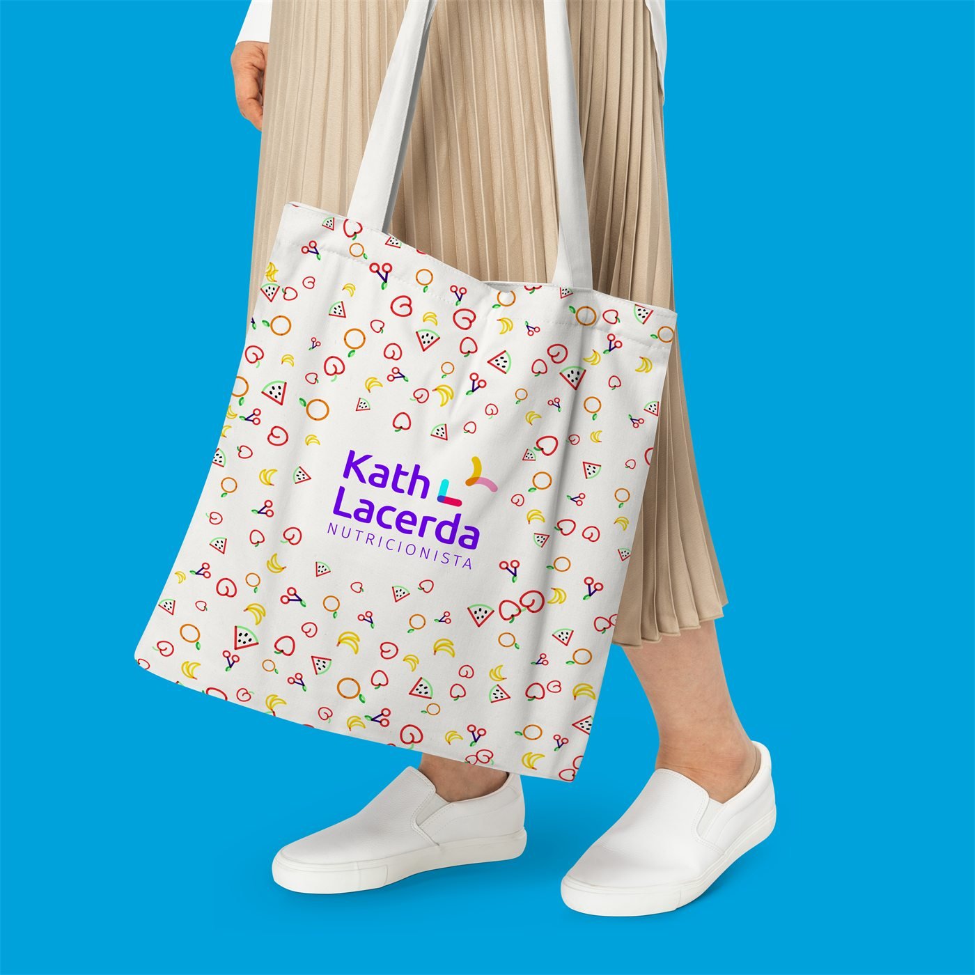 Mulher carrega a ecobag branca com estampa de frutas e a assinatura Kath Lacerda Nutricionista