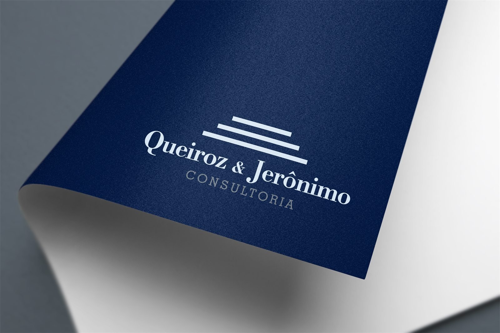 A marca Queiroz & Jerônimo Consultoria em branco sobre papel azul-marinho, com o canto da folha dobrado