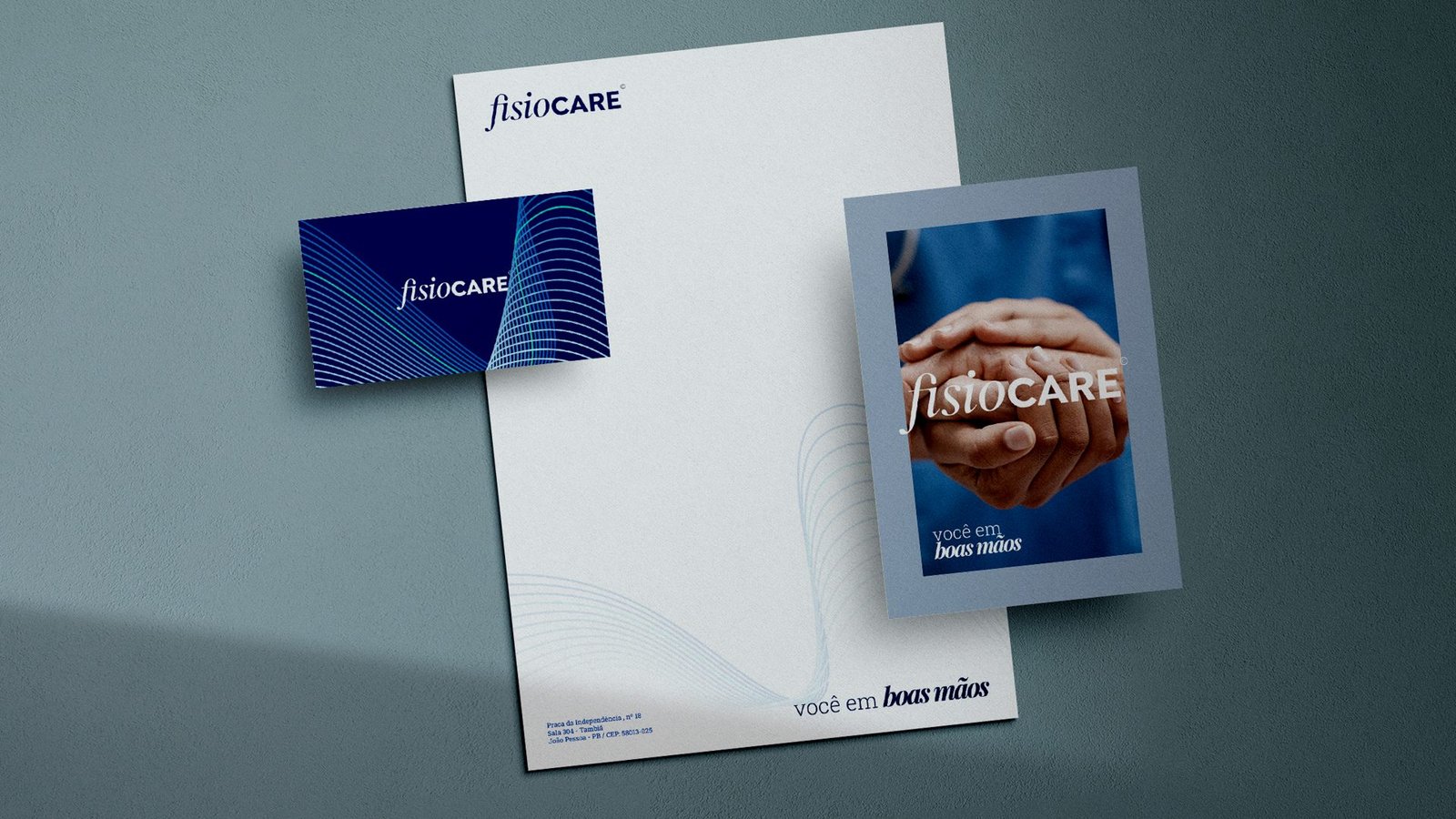 Papelaria da Fisiocare: papel timbrado, cartão de visita azul e cartão com mãos dadas e a frase você em boas mãos
