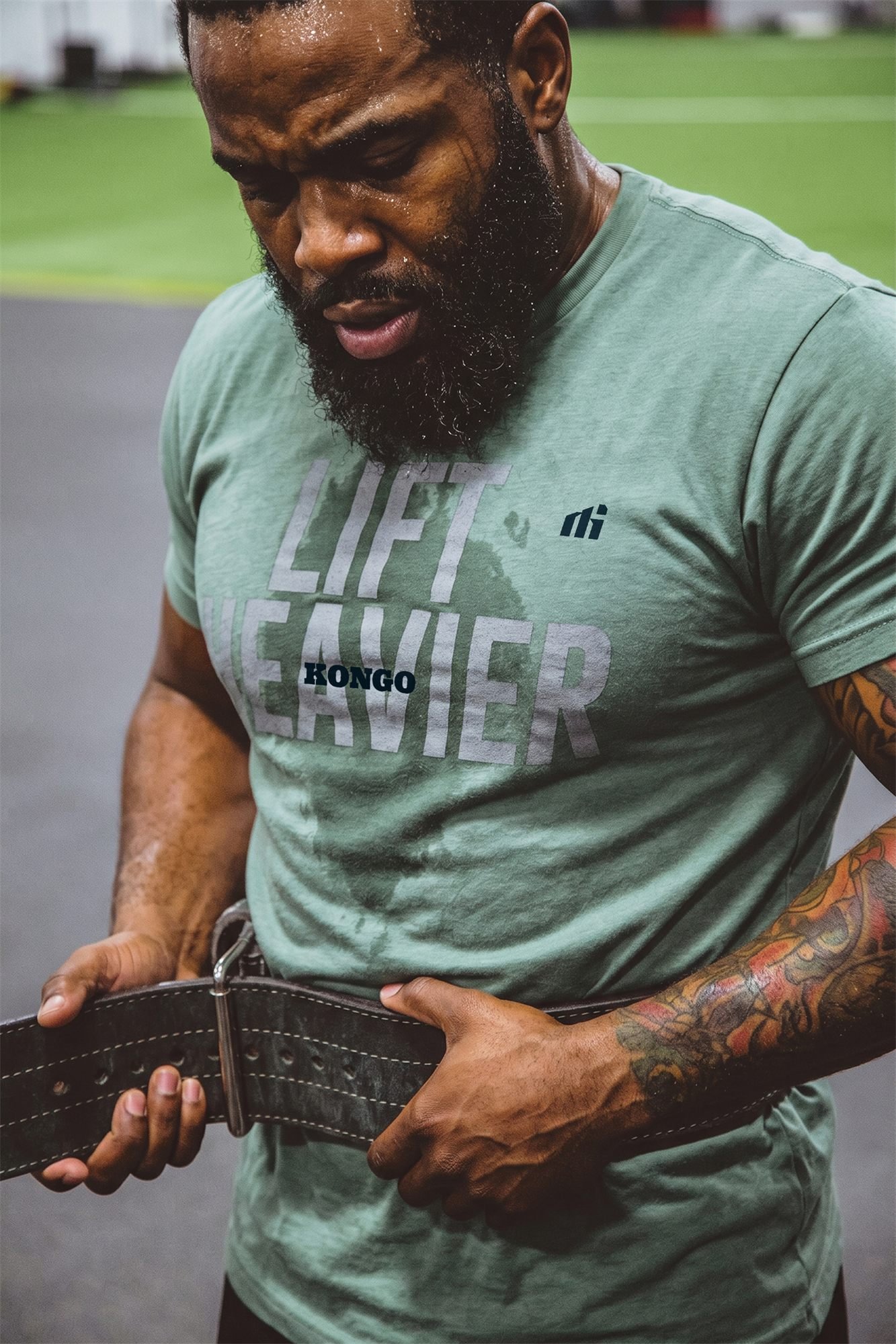 Atleta ajusta o cinto de levantamento, com a camiseta da Kongo
